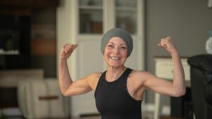 Femme souriante les bras levés qui utiliser l'activité physique adaptée pour accompagner sa guérison du cancer du sein 